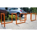 Stojak rowerowy Irys V - pomarańczowe stojaki na kostce przed parkingiem