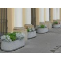 Donica owalna 158x74x78 - rząd donic z roślinami przed kolumnami budynku